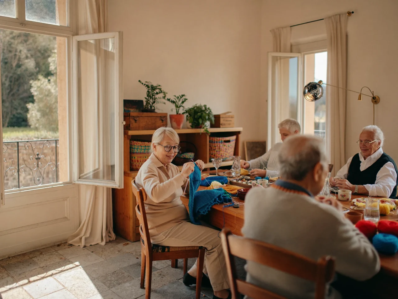 Sala creativa luminosa con persone mature al lavoro attorno a un lungo tavolo