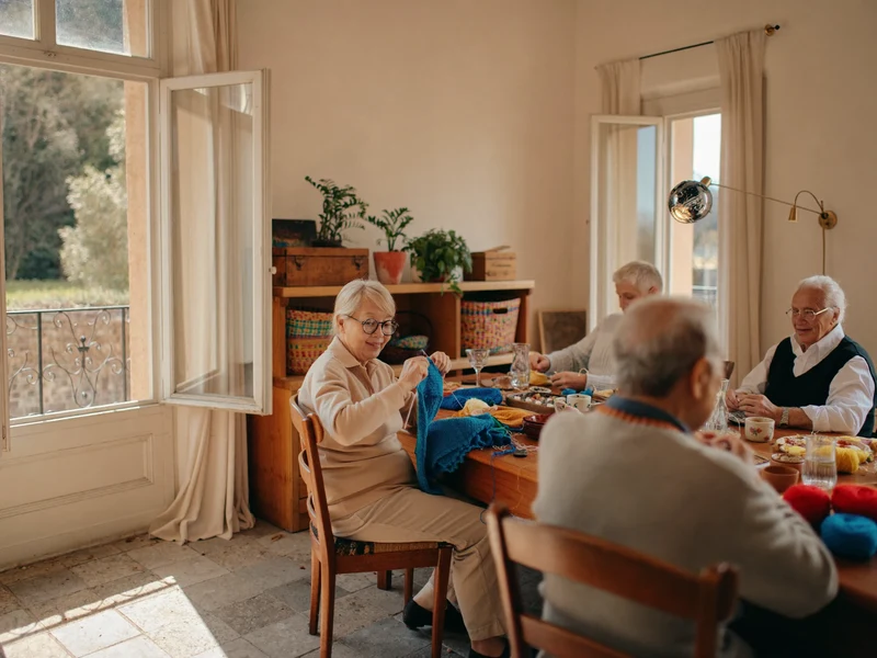 Sala creativa luminosa con persone mature al lavoro attorno a un lungo tavolo